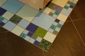 photo of geometric tile to create a floor rug around kitchen island by Kitchen Designs by Ken Kelly Long Island showroom